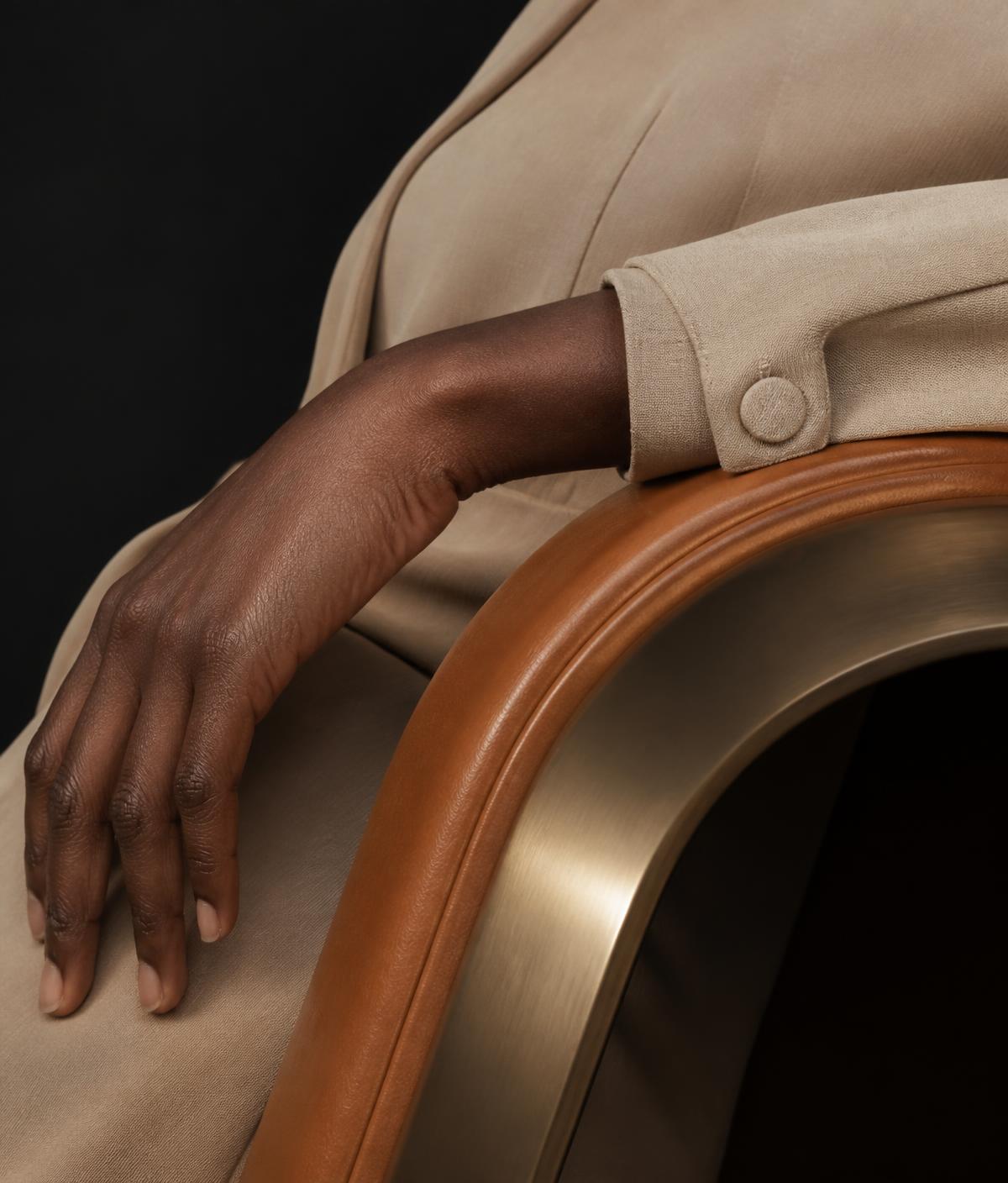 A hand resting on the sculpted leather and brass curve of an ergonomic form